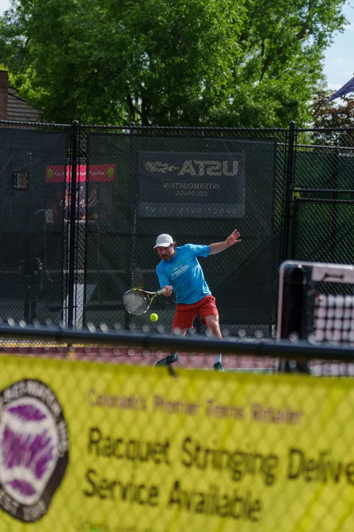 Player hitting low forehand with USTA banner visible